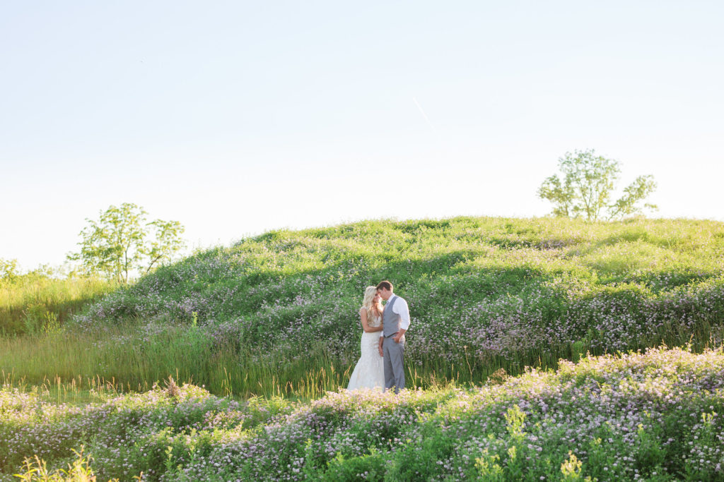 classy bride and groom posing in hills of wildflowers