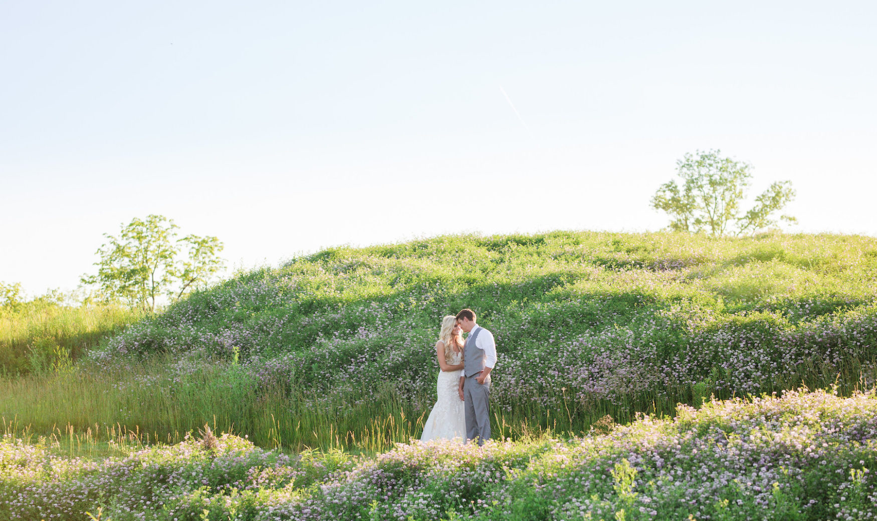classy bride and groom posing in hills of wildflowers
