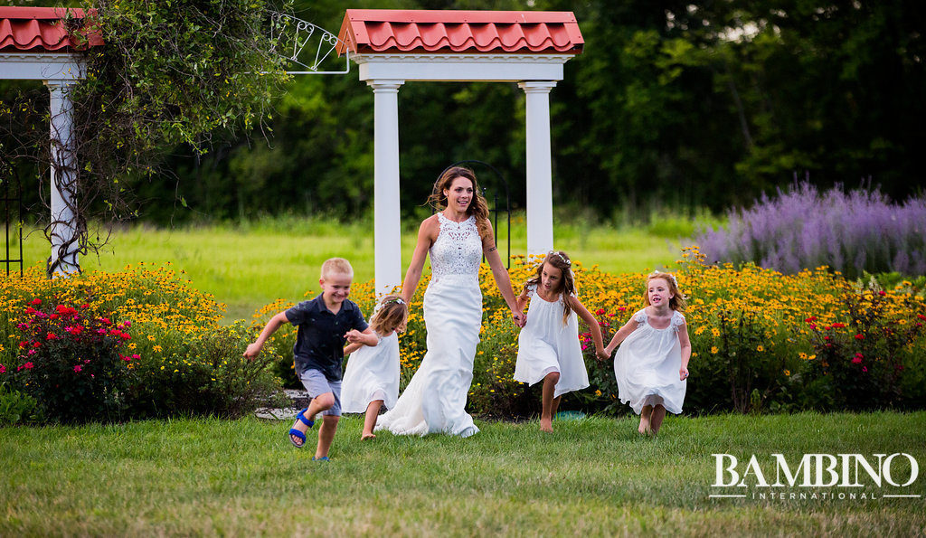 Bride with children running in the flowerbeds.