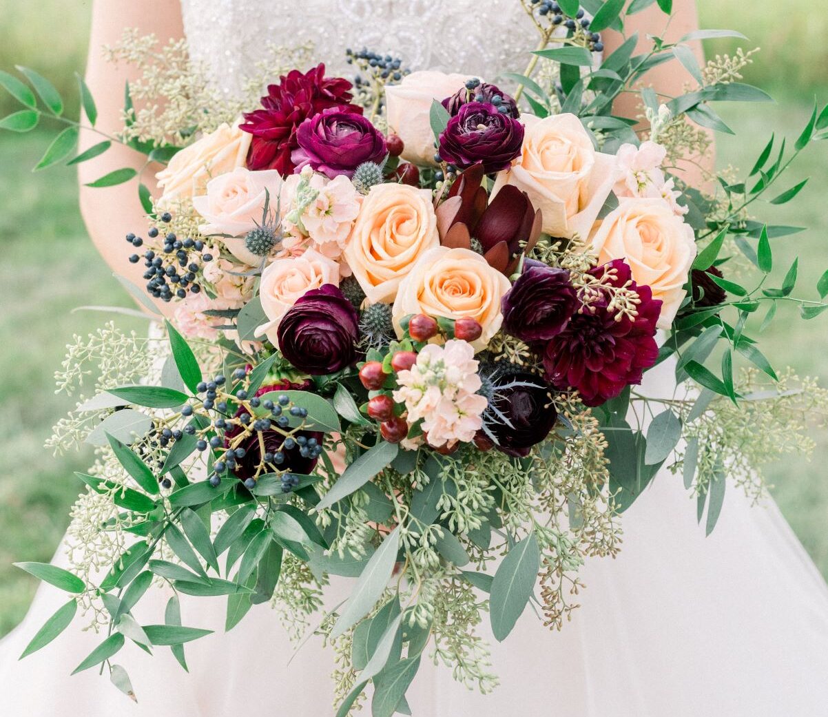 elegant bride in meadow holding chic bouquet of flowers