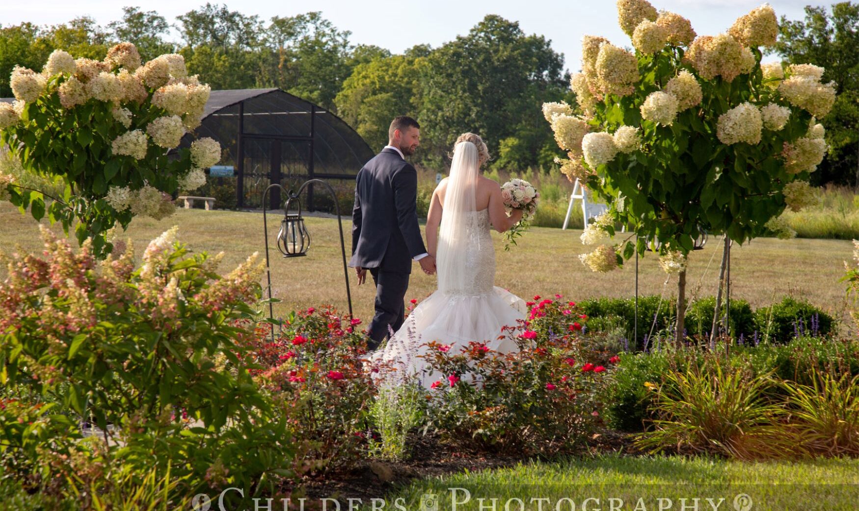 Bride and groom walking down the aisle way with hydrangea trees