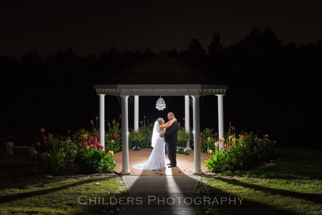 bride and groom posing under garden gazebo