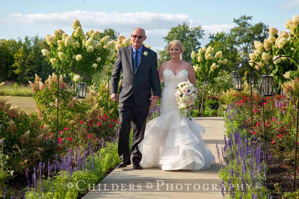 elegant bride walking down garden floral wedding aisle