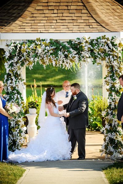 bride and groom being wed under tropical flower gazebo