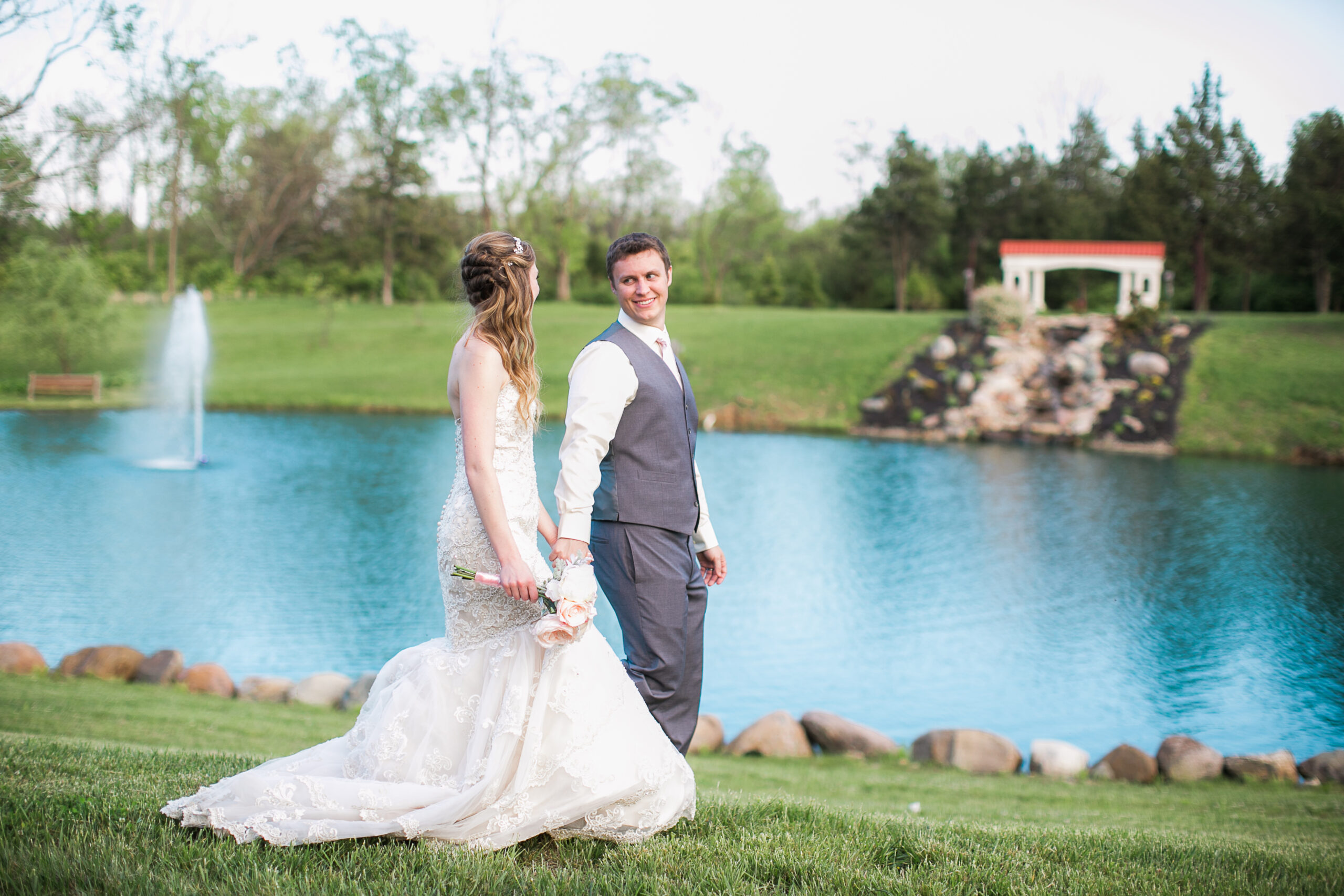 bride and groom walking by tropical looking pond